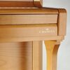 Détail d'un piano droit en bois clair.
