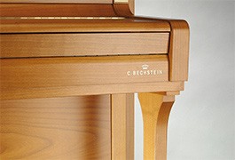 Détail d'un piano droit en bois clair.
